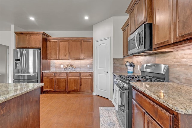 13640 Ridge View Ln, Edmond, OK 73025 - kitchen featuring appliances with stainless steel finishes, decorative backsplash, light stone counters, brown cabinets, and recessed lighting