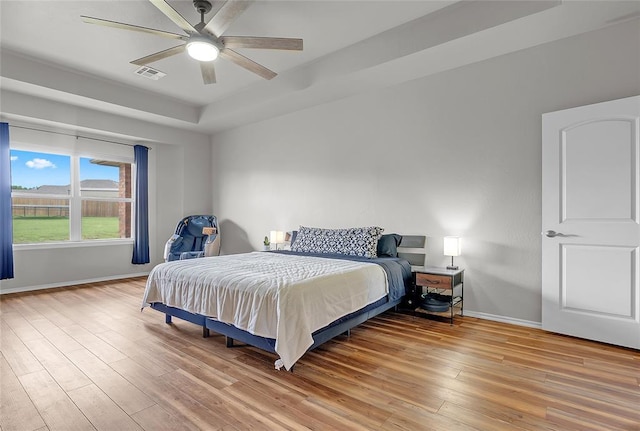13640 Ridge View Ln, Edmond, OK 73025 - bedroom featuring light wood-type flooring, a raised ceiling, and a ceiling fan