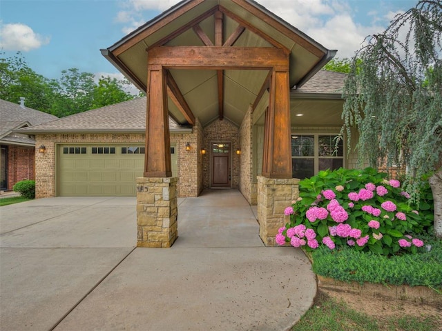 2120 Turtle Creek Dr, Norman, OK 73071 - view of exterior entry with an attached garage, concrete driveway, roof with shingles, and brick siding