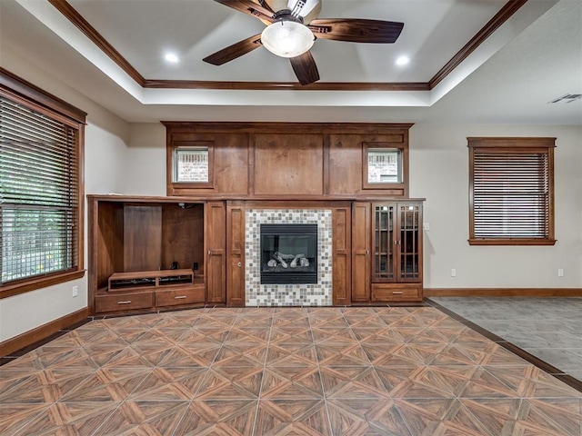 2120 Turtle Creek Dr, Norman, OK 73071 - unfurnished living room featuring baseboards, a tiled fireplace, crown molding, a raised ceiling, and ceiling fan