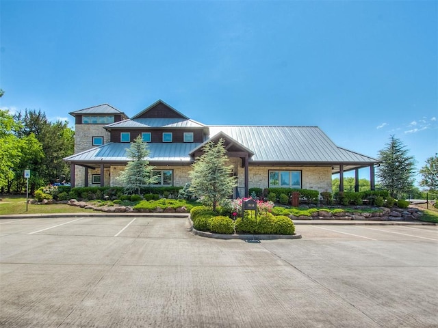 2120 Turtle Creek Dr, Norman, OK 73071 - view of front of property featuring a standing seam roof, stone siding, uncovered parking, and metal roof