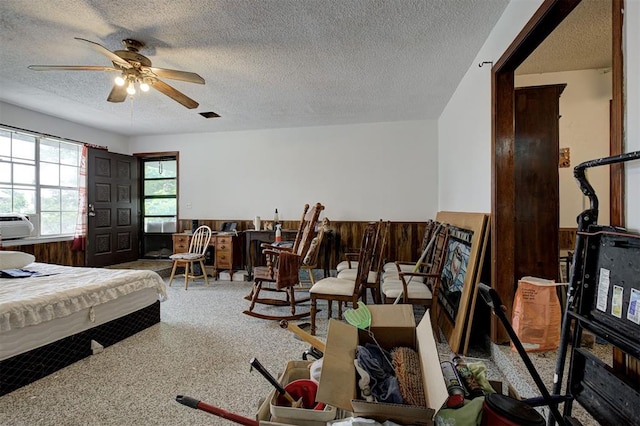 407 S Norman Ave, Moore, OK 73160 - bedroom with a textured ceiling, wainscoting, wooden walls, cooling unit, and a ceiling fan