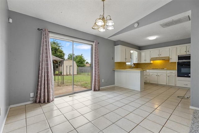 616 Willow Ridge Pl, Edmond, OK 73003 - kitchen featuring oven, under cabinet range hood, a textured ceiling, lofted ceiling, and a chandelier