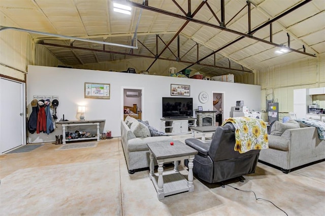 living area featuring concrete flooring, high vaulted ceiling, and water heater