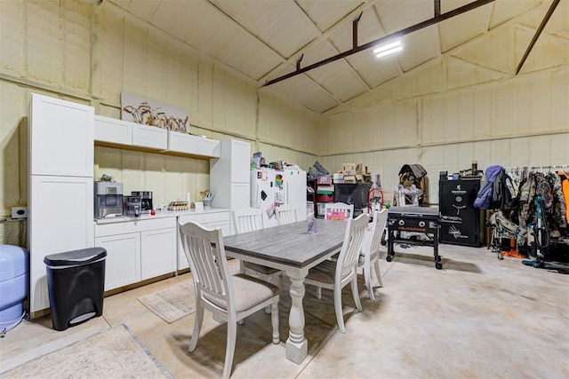 dining area featuring concrete floors and high vaulted ceiling
