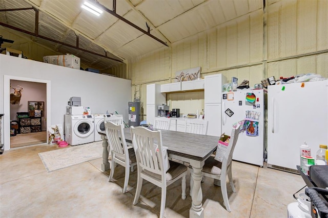 dining space featuring concrete flooring, water heater, washing machine and clothes dryer, and high vaulted ceiling