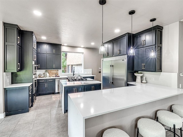 2113 Highlands Lndg, Edmond, OK 73013 - kitchen with stainless steel built in refrigerator, a peninsula, light countertops, a breakfast bar, and recessed lighting