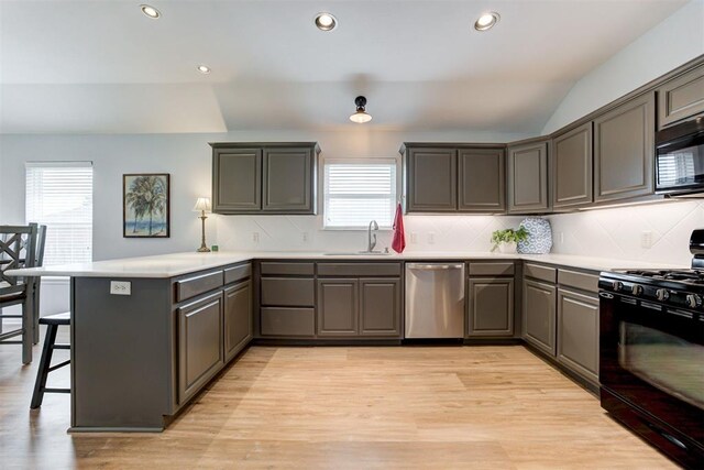 405 Bright Angel Trl, Edmond, OK 73003 - kitchen featuring black appliances, a sink, a peninsula, a kitchen bar, and plenty of natural light
