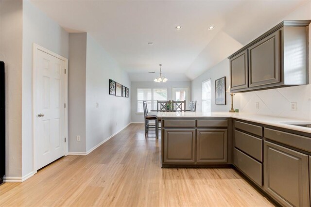 405 Bright Angel Trl, Edmond, OK 73003 - kitchen with a chandelier, light wood finished floors, a peninsula, vaulted ceiling, and light countertops