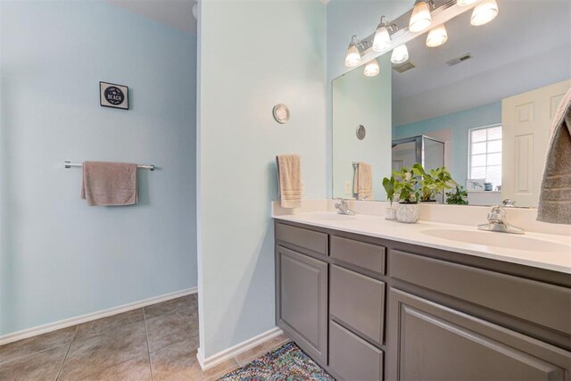 405 Bright Angel Trl, Edmond, OK 73003 - bathroom featuring double vanity, tile patterned flooring, a shower with shower door, and baseboards