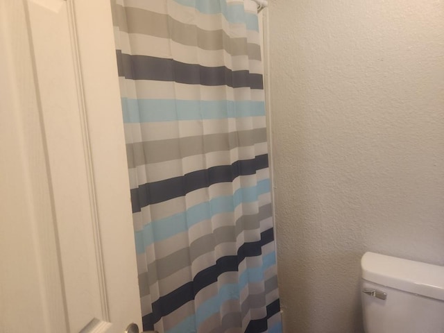 1003 E Whittaker St, Shawnee, OK 74801 - full bath featuring toilet, a textured wall, and a shower with curtain
