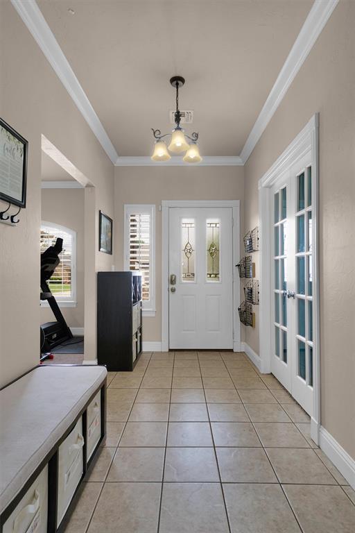 1204 Sheryl Ln, Altus, OK 73521 - foyer entrance with french doors, crown molding, light tile patterned flooring, a chandelier, and baseboards