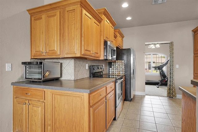 1204 Sheryl Ln, Altus, OK 73521 - kitchen featuring appliances with stainless steel finishes, decorative backsplash, light tile patterned floors, baseboards, and dark countertops
