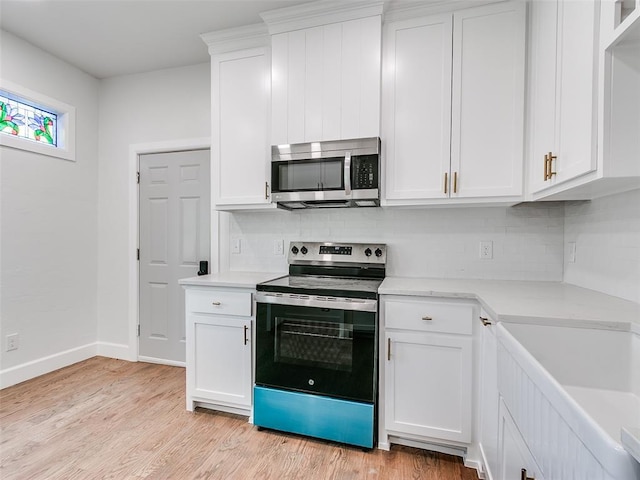 801 N Ash St, Guthrie, OK 73044 - kitchen featuring appliances with stainless steel finishes, backsplash, light wood-type flooring, and white cabinetry