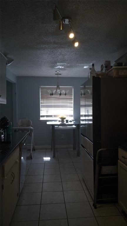 428 NW 91st St, Oklahoma City, OK 73114 - kitchen featuring freestanding refrigerator, white cabinetry, a textured ceiling, light tile patterned flooring, and a chandelier