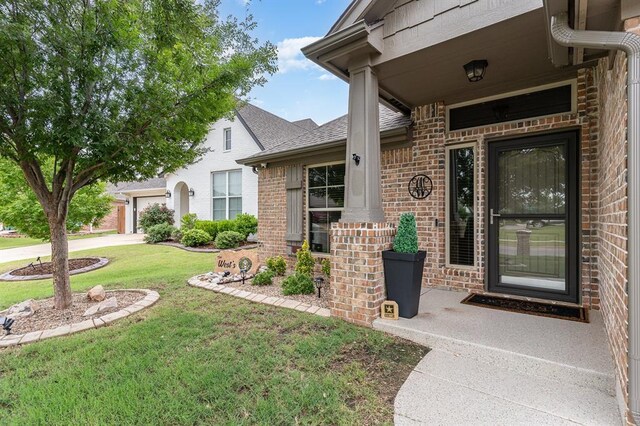 17912 Marron Dr, Edmond, OK 73012 - view of exterior entry featuring a yard, brick siding, an attached garage, driveway, and roof with shingles