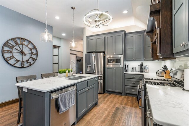 17912 Marron Dr, Edmond, OK 73012 - kitchen with stainless steel appliances, a sink, a kitchen breakfast bar, wood finished floors, and recessed lighting