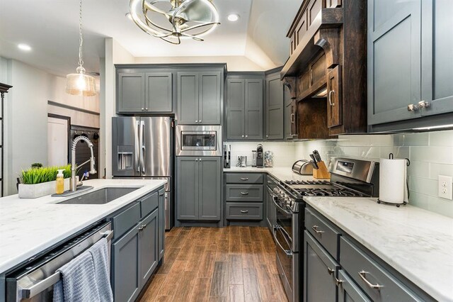 17912 Marron Dr, Edmond, OK 73012 - kitchen featuring stainless steel appliances, a sink, dark wood-type flooring, light stone counters, and pendant lighting