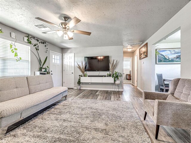 621 W 2nd St, Calumet, OK 73014 - living room featuring wood finished floors, a textured ceiling, a ceiling fan, and baseboards