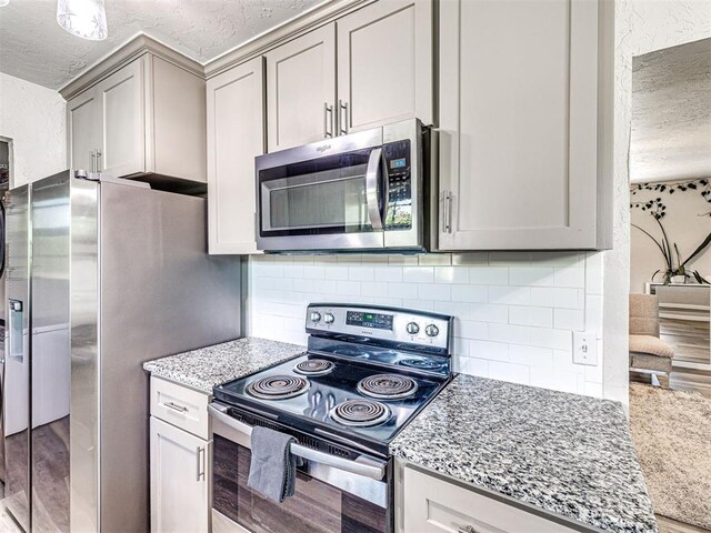 621 W 2nd St, Calumet, OK 73014 - kitchen with appliances with stainless steel finishes, a textured ceiling, light stone countertops, light wood-style flooring, and backsplash