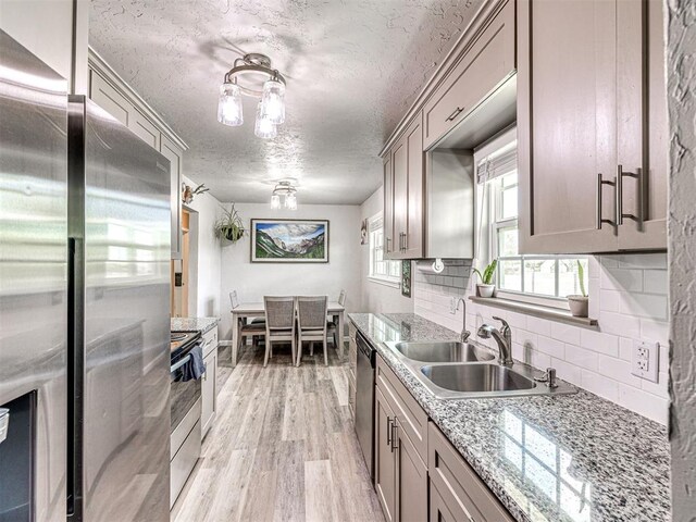 621 W 2nd St, Calumet, OK 73014 - kitchen featuring stainless steel appliances, a textured ceiling, a sink, light wood finished floors, and tasteful backsplash