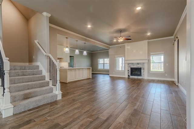 12916 Ponderosa Blvd, Oklahoma City, OK 73142 - unfurnished living room featuring crown molding, plenty of natural light, ceiling fan, dark wood-type flooring, and stairs