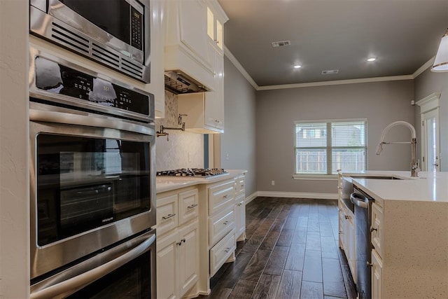 12916 Ponderosa Blvd, Oklahoma City, OK 73142 - kitchen featuring stainless steel appliances, a sink, tasteful backsplash, baseboards, and crown molding