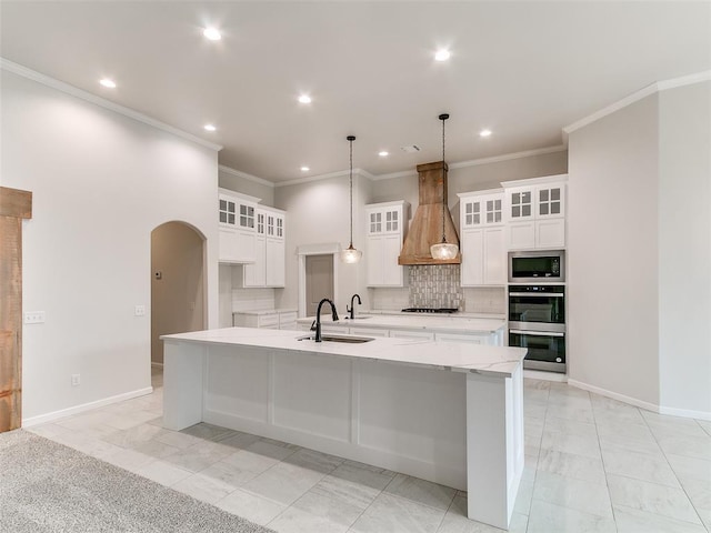 14613 Brantwood Cir, Oklahoma City, OK 73142 - kitchen with custom exhaust hood, appliances with stainless steel finishes, a spacious island, a sink, and arched walkways