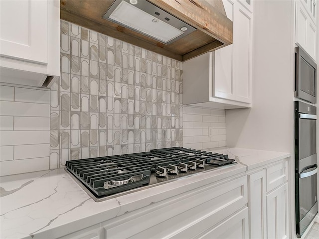 14613 Brantwood Cir, Oklahoma City, OK 73142 - kitchen with stainless steel appliances, range hood, white cabinets, and tasteful backsplash