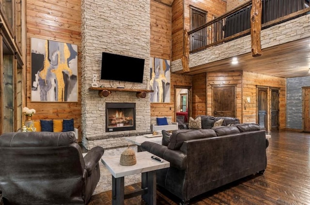 31 Conifer Crossing Trl, Broken Bow, OK 74728 - living room featuring a towering ceiling, wood walls, a stone fireplace, and hardwood / wood-style floors