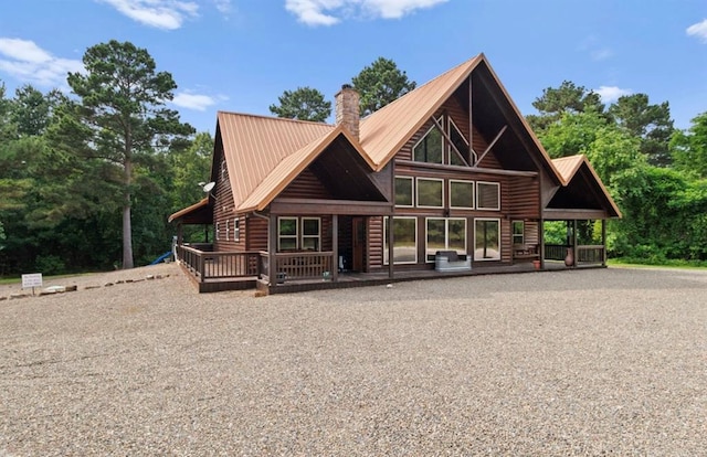 170 Driftcast Rd, Broken Bow, OK 74728 - view of front of house with log veneer siding, a chimney, metal roof, and a deck