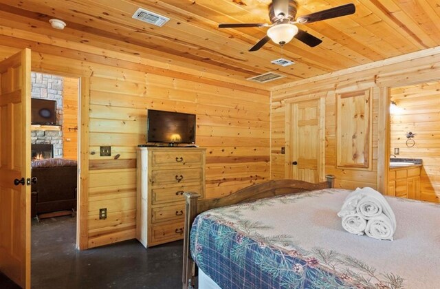 170 Driftcast Rd, Broken Bow, OK 74728 - bedroom featuring wood ceiling, wooden walls, a stone fireplace, concrete floors, and ensuite bathroom