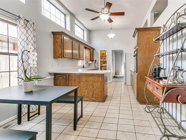 16716 Valley Crst, Edmond, OK 73012 - kitchen featuring a peninsula, ceiling fan, a high ceiling, light tile patterned floors, and light countertops