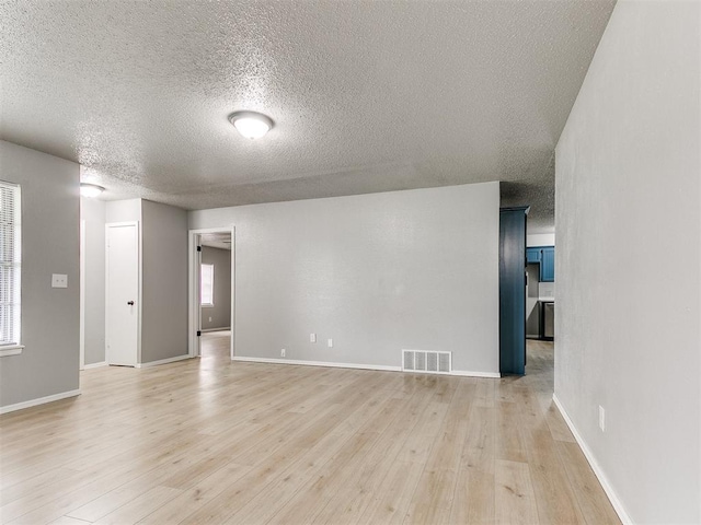 2713 SW 75th St, Oklahoma City, OK 73159 - empty room featuring a textured ceiling, light wood-type flooring, and baseboards