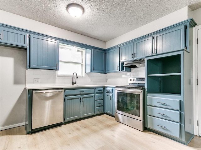 2713 SW 75th St, Oklahoma City, OK 73159 - kitchen featuring stainless steel appliances, under cabinet range hood, decorative backsplash, light wood-type flooring, and a textured ceiling