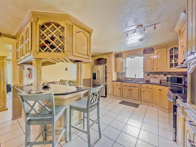 1117 SW 37th St, Oklahoma City, OK 73109 - kitchen with stainless steel appliances, light tile patterned floors, a sink, tasteful backsplash, and dark countertops