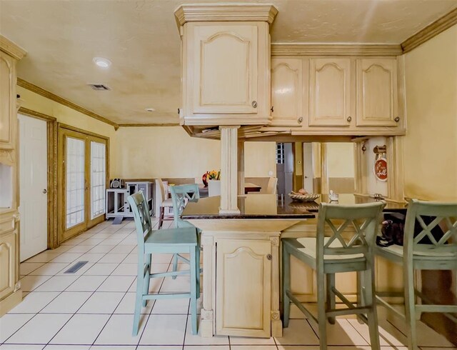 1117 SW 37th St, Oklahoma City, OK 73109 - kitchen with french doors, dark countertops, ornamental molding, light tile patterned floors, and a kitchen bar