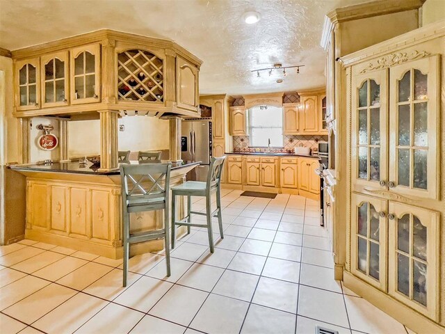 1117 SW 37th St, Oklahoma City, OK 73109 - kitchen featuring light tile patterned floors, a sink, glass insert cabinets, tasteful backsplash, and track lighting
