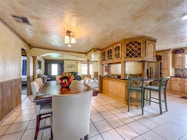 1117 SW 37th St, Oklahoma City, OK 73109 - dining area featuring arched walkways, decorative columns, ornamental molding, light tile patterned floors, and a textured ceiling