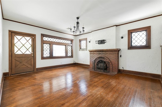 1505 NW 34th St, Oklahoma City, OK 73118 - unfurnished living room with a chandelier, ornamental molding, wood-type flooring, baseboards, and a brick fireplace