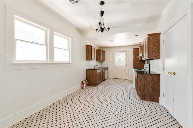 1505 NW 34th St, Oklahoma City, OK 73118 - kitchen with gas range gas stove, dark countertops, a sink, brown cabinetry, and a chandelier