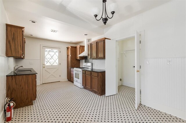 1505 NW 34th St, Oklahoma City, OK 73118 - kitchen with white gas range, dark countertops, wainscoting, a sink, and light floors
