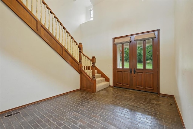 2108 Woodhill Rd, Edmond, OK 73025 - foyer featuring brick flooring, a towering ceiling, stairway, and baseboards