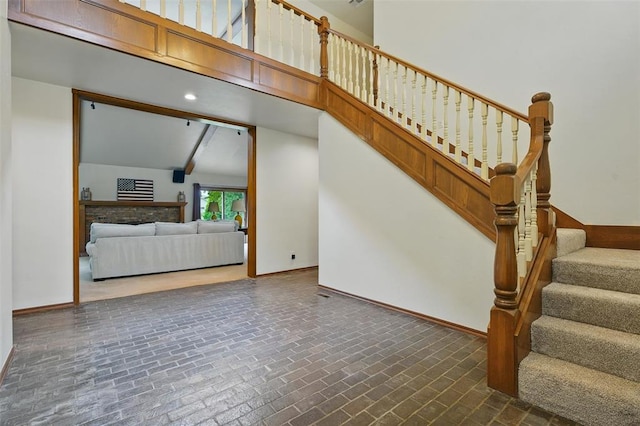 2108 Woodhill Rd, Edmond, OK 73025 - stairs featuring brick patterned flooring, baseboards, a high ceiling, and beamed ceiling