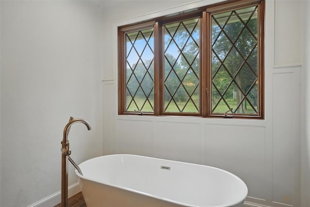 2108 Woodhill Rd, Edmond, OK 73025 - bathroom featuring a decorative wall, a soaking tub, and baseboards