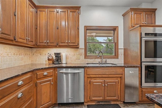 2108 Woodhill Rd, Edmond, OK 73025 - kitchen featuring appliances with stainless steel finishes, a sink, brown cabinets, and dark stone countertops