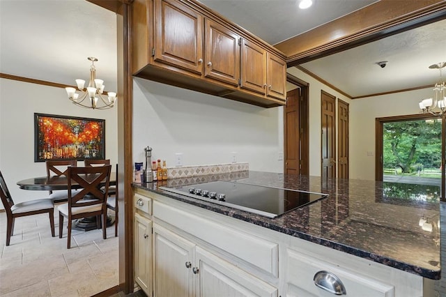 2108 Woodhill Rd, Edmond, OK 73025 - kitchen featuring a chandelier, black electric stovetop, crown molding, hanging light fixtures, and dark stone countertops
