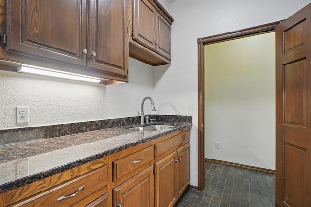2108 Woodhill Rd, Edmond, OK 73025 - kitchen featuring a sink, dark stone countertops, and baseboards