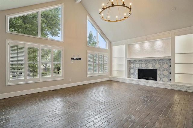 2108 Woodhill Rd, Edmond, OK 73025 - unfurnished living room with brick patterned floors, a chandelier, built in shelves, high vaulted ceiling, and baseboards