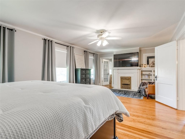 1218 NW 21st St, Oklahoma City, OK 73106 - bedroom featuring a fireplace, light wood finished floors, crown molding, and a ceiling fan